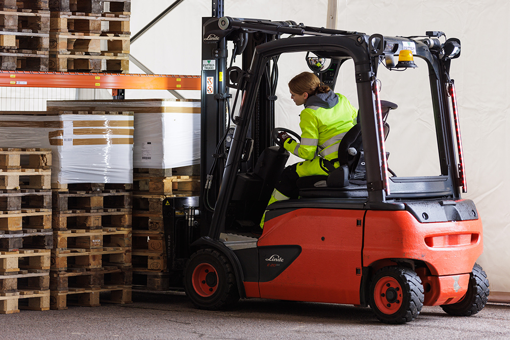 Nuori nainen siirtää kuormalavoja turkilla varastossa.