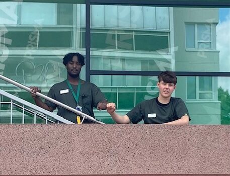 Benjamin ja Eelis seisomassa portaikon kaiteen takana kameraan päin. 