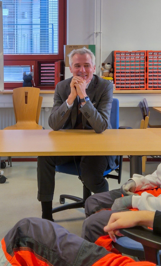 Anders Adlercreuz istumassa pulpetin takana kuunnellen etualalla olevien opiskelijoiden kysymyksiä. 