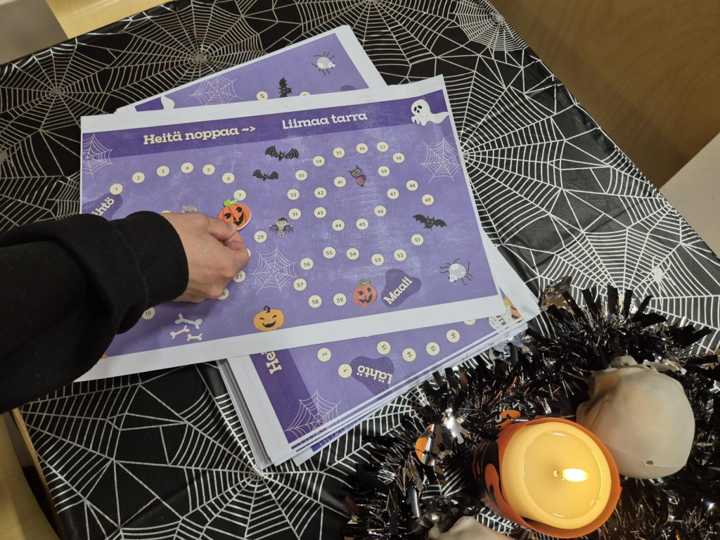 Käsivarsi pitää pelinappulaa lautapelilaudan päällä. 