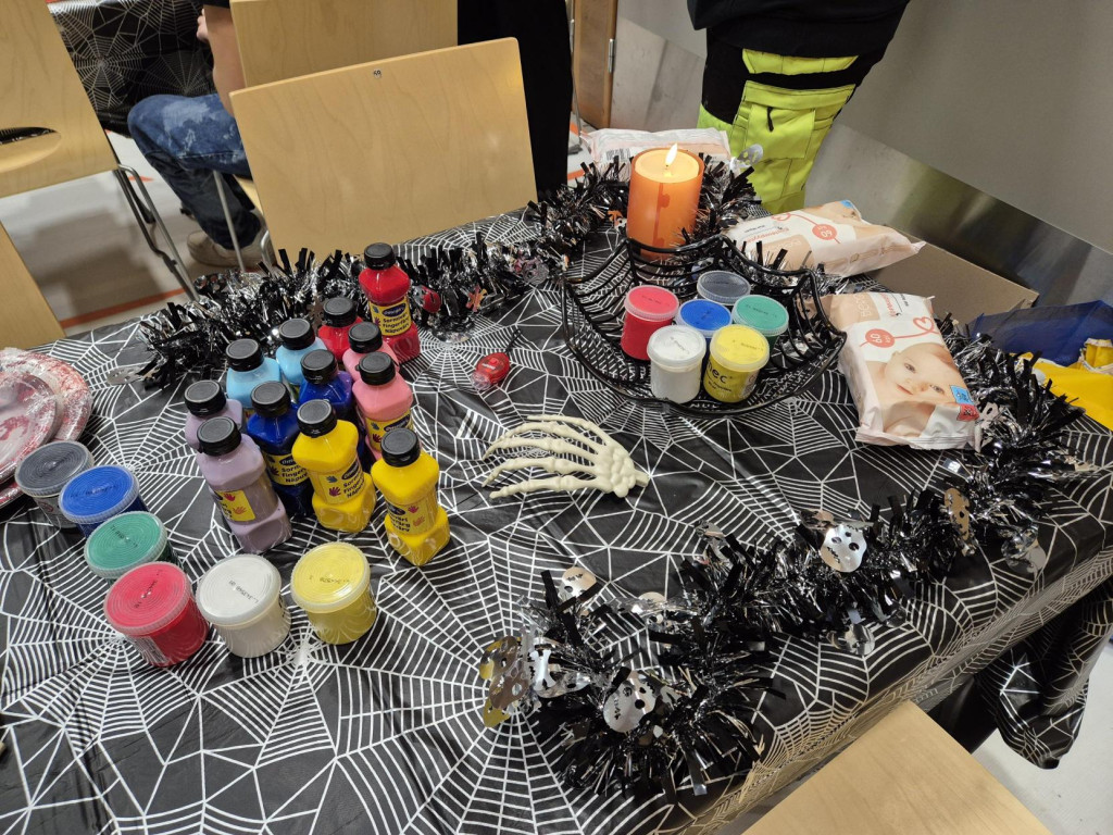 Maalaustarvikkeita ja halloween-koristeita pöydällä.