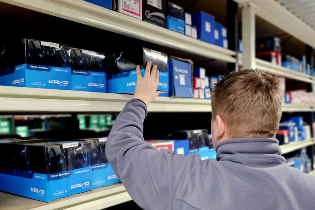 Mies ojentaa kättään ruuvilaatikoita kohti, näkyy käsi hartiat.