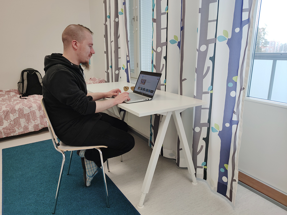 Opiskelija tietokoneen ääressä opiskelija-asuntolassa.