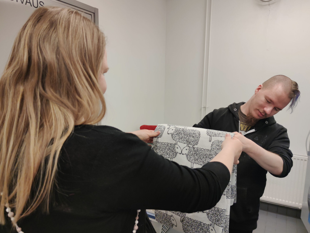 Lakanan viikkausta asuntolassa, opiskelija ja ohjaaja yhdessä.