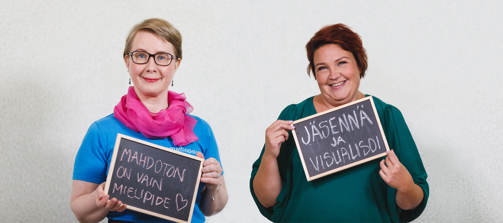 Maria Ojala-Vesteri ja Marika Mäkinen seisovat vierekkäin käsissään liitutaulut, joissa Marialla lukee "Mahdoton on vain mielipide"