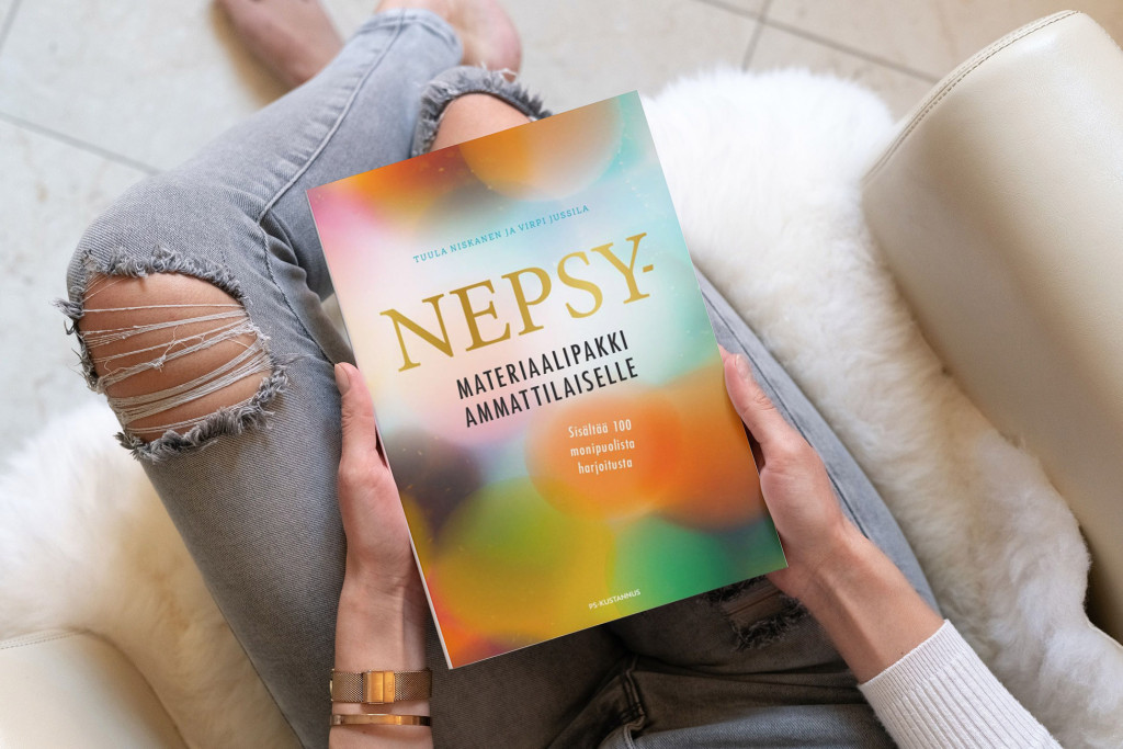 Nepsy-materiaalipakki kirja tuolilla istuvan henkilön sylissä.