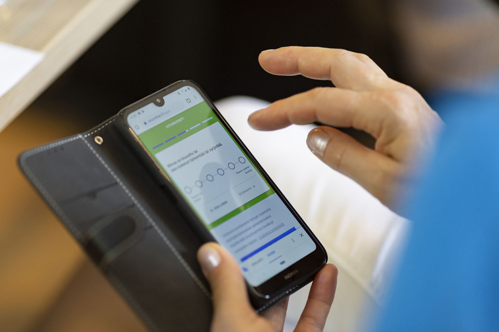 Puhelimen ruudulla on auki kysely, johon käsi näpyttelee vastauksia.